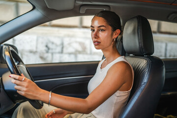 Young beautiful woman drive a car through the city