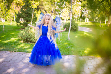 Little girl dressed as a fairy on the background of the park. The concept of a magical holiday....