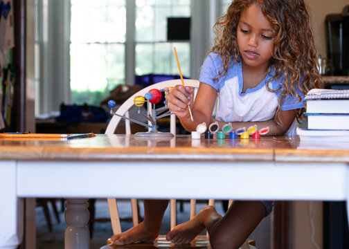 Young girl painting solar system model