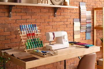 Tailor's workplace with sewing machine and thread spools in atelier