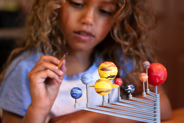 Young girl painting solar system model