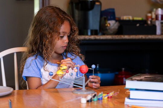 Young girl painting solar system model - Powered by Adobe