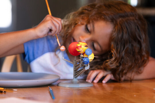 Young girl painting solar system model