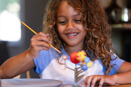 Young girl painting solar system model