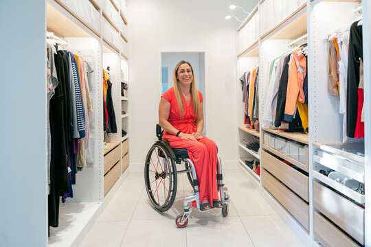 Woman in wheelchair smiling in modern walk-in closet