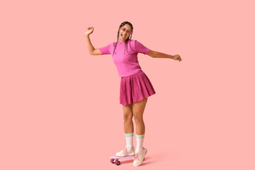 Beautiful young African-American woman with dreadlocks and skateboard on pink background