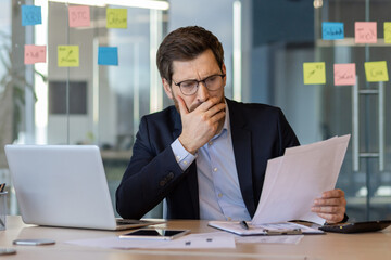 Businessman analyzing financial documents in modern office setting