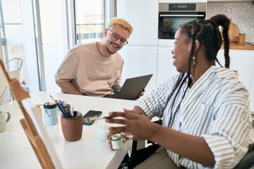 Multiracial colleagues enjoying productive brainstorming session in modern office space with laptops and supplies spread on the table, sharing ideas and insights