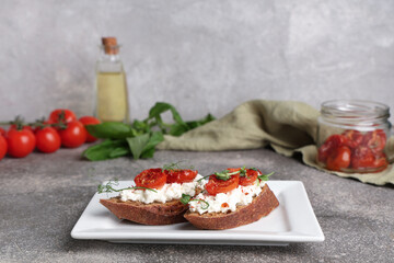 Plate of tasty tomato bruschetta with ricotta on grey background