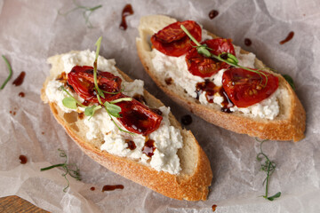 Baking paper of tasty tomato bruschetta with ricotta on table, closeup