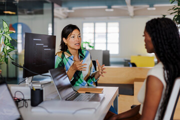Project manager explaining strategy to programmer in open plan office