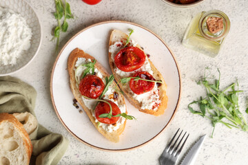 Plate of tasty tomato bruschetta with ricotta and micro green on white background