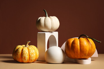 Decorative podiums with fresh pumpkins on brown background