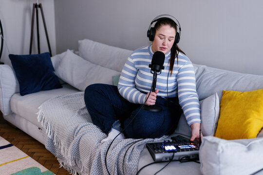 Plus size podcaster pushing button on audio mixer to adjust sound