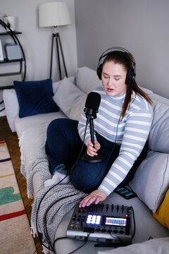 Plus size woman pushing button on audio mixer to improve content sound
