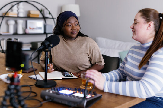 Plus size woman interviewing colleague for podcast in living room