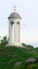 Fototapeta premium beautiful landscape and a small bell tower. a detail of the building a small bell tower with a cross stands on a hill. faith, religion. space for text. Christianity or Catholicism. autumn time