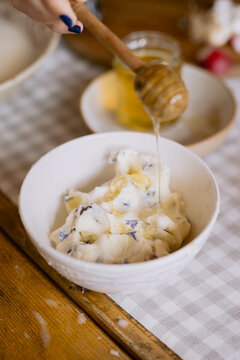Creamy dish being drizzled with honey on table.