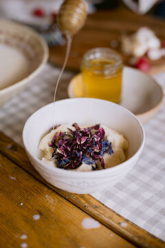 Honey drizzling onto a creamy flower-topped dish.