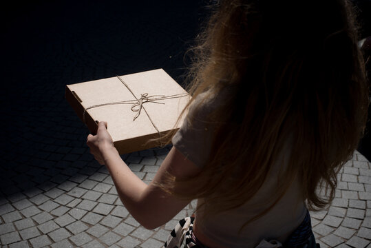 Woman holding pizza box tied with string 