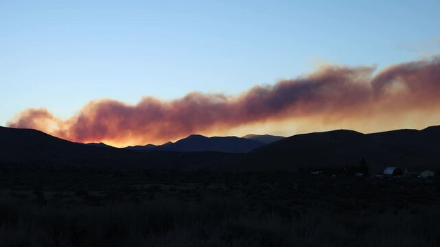 Time lapsed plume of smoke from wildfire over mountains after the sun went down.