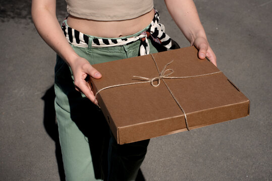 Woman holding pizza box tied with string 