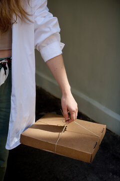 Woman Holding Cardboard Pizza Box Tied With String 