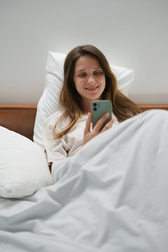 Relaxed Woman Using Smartphone in Bed