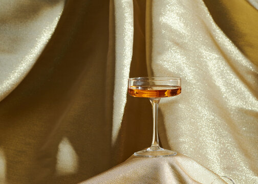 Wine glass on golden satin curtain background