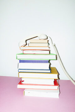 Colorful stack of books & old landline phone on office business desk