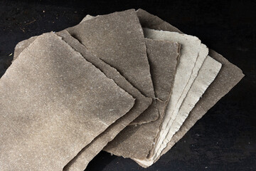 Nahaufnahme von handgeschöpften Papierseiten aus Flachs vor dunklem Hintergrund.