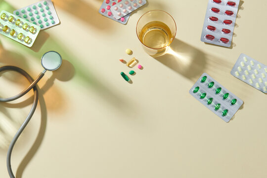 Colorful pills with glass of clear water and a stethoscope