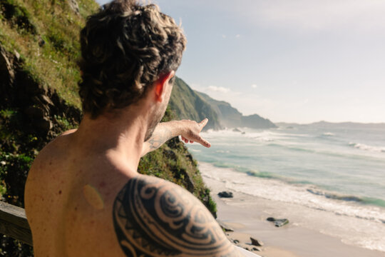 Surfer pointing towards the horizon, spotting the perfect surf spot