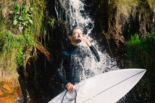 A skilled surfer takes a plunge under a cascade of water