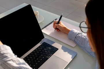 Lady laboring from home makes notes during a remote work session