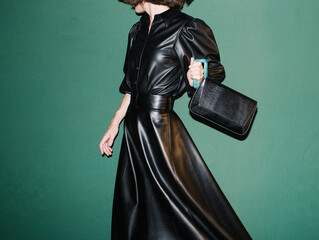 Fashionable Woman in Black Leather Dress Holding a Stylish Handb