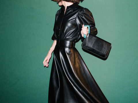 Fashionable Woman in Black Leather Dress Holding a Stylish Handb