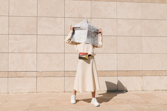 Person in Minimalist Style Holding a Large Map Against a Beige W