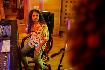 Music producer at music studio near channel mixer and listening songs.