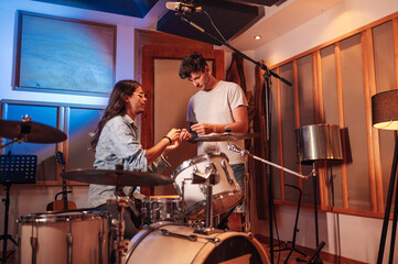 Musician discussing with sound technician at music recording studio.