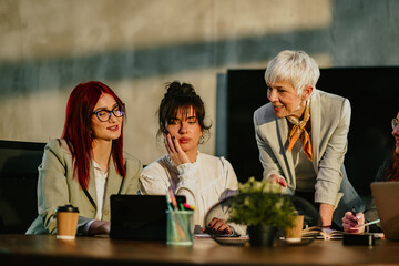 Mature manager tutoring and teaching her young staff at conference room