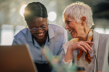 Smiling interracial female entrepreneurs collaborating on a project.