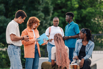 Interracial group of college classmates chatting and studying at campus