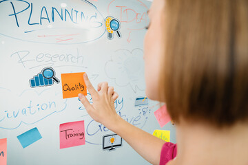 Closeup of professional businesswoman hand put and stick the colorful sticky notes on whiteboard while presenting business plan. Creative business meeting and brainstorming concept. Immaculate.