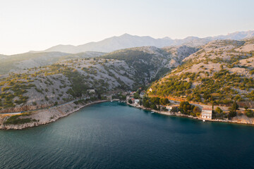 Fototapeta premium Coastal landscape at sunset overlooking a tranquil bay with mountains in the distance. 