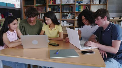 Young group of diverse students studying together using laptop at library. College multiracial people working on group assignment homework project at university. - Powered by Adobe