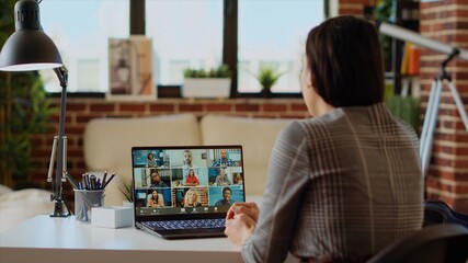 Teleworking management executive in apartment discussing with coworkers during videoconference...