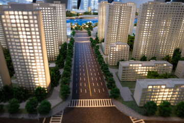 A detailed and illuminated model of a modern city, featuring a wide, multi-lane road lined with...