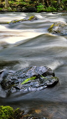 Long exposure of flowing water over rocks in the forest producing waterfalls