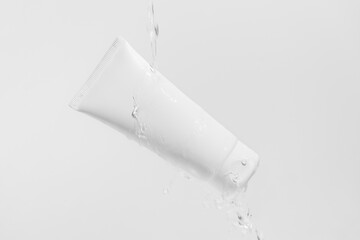 White cream tube mockup with water stream and drops pouring from above on isolated background. The concept of face and body care, aesthetics and beauty. Image for your design